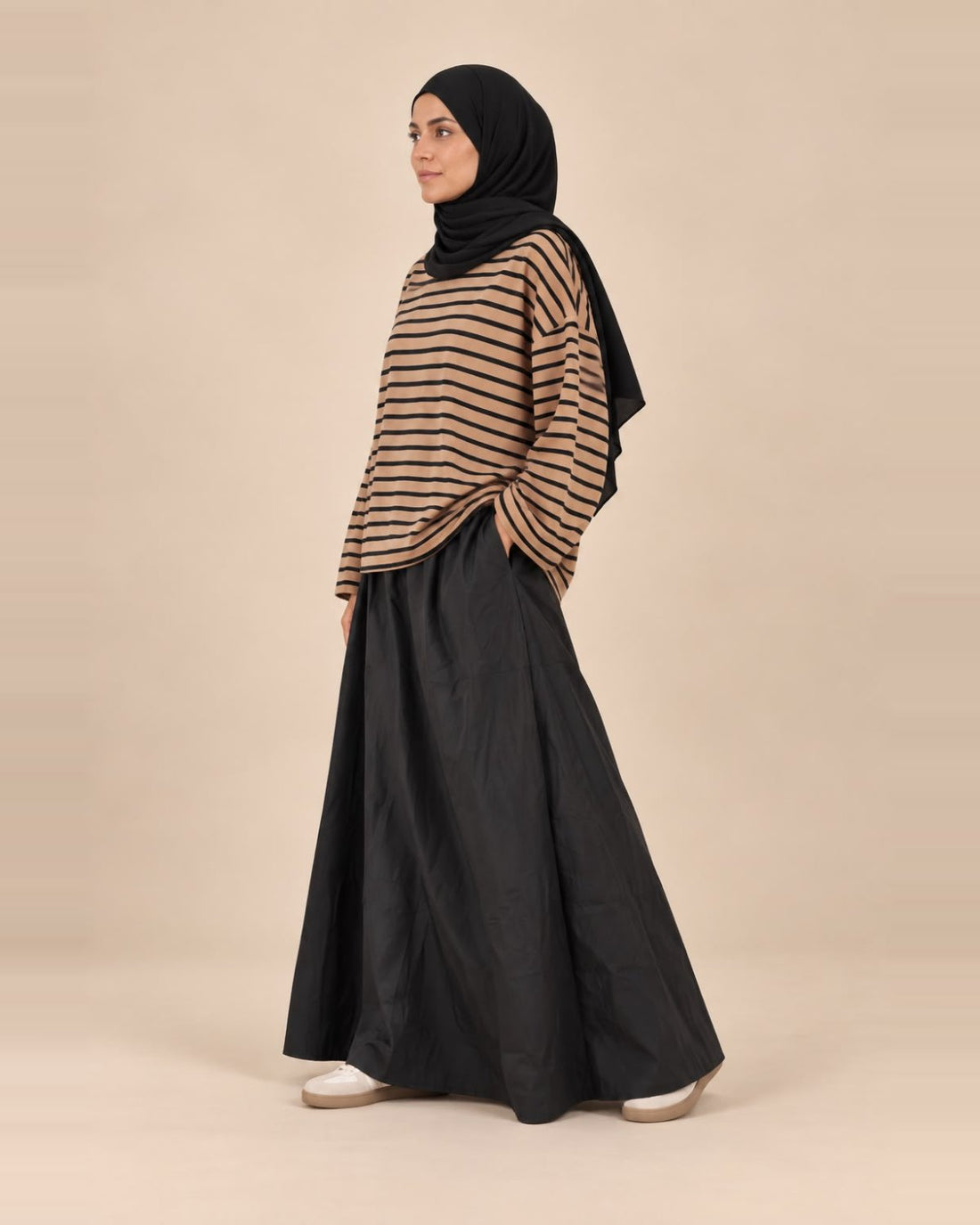 Jupe longue en coton doublée noire portée avec un haut ample rayé camel, vue de profil